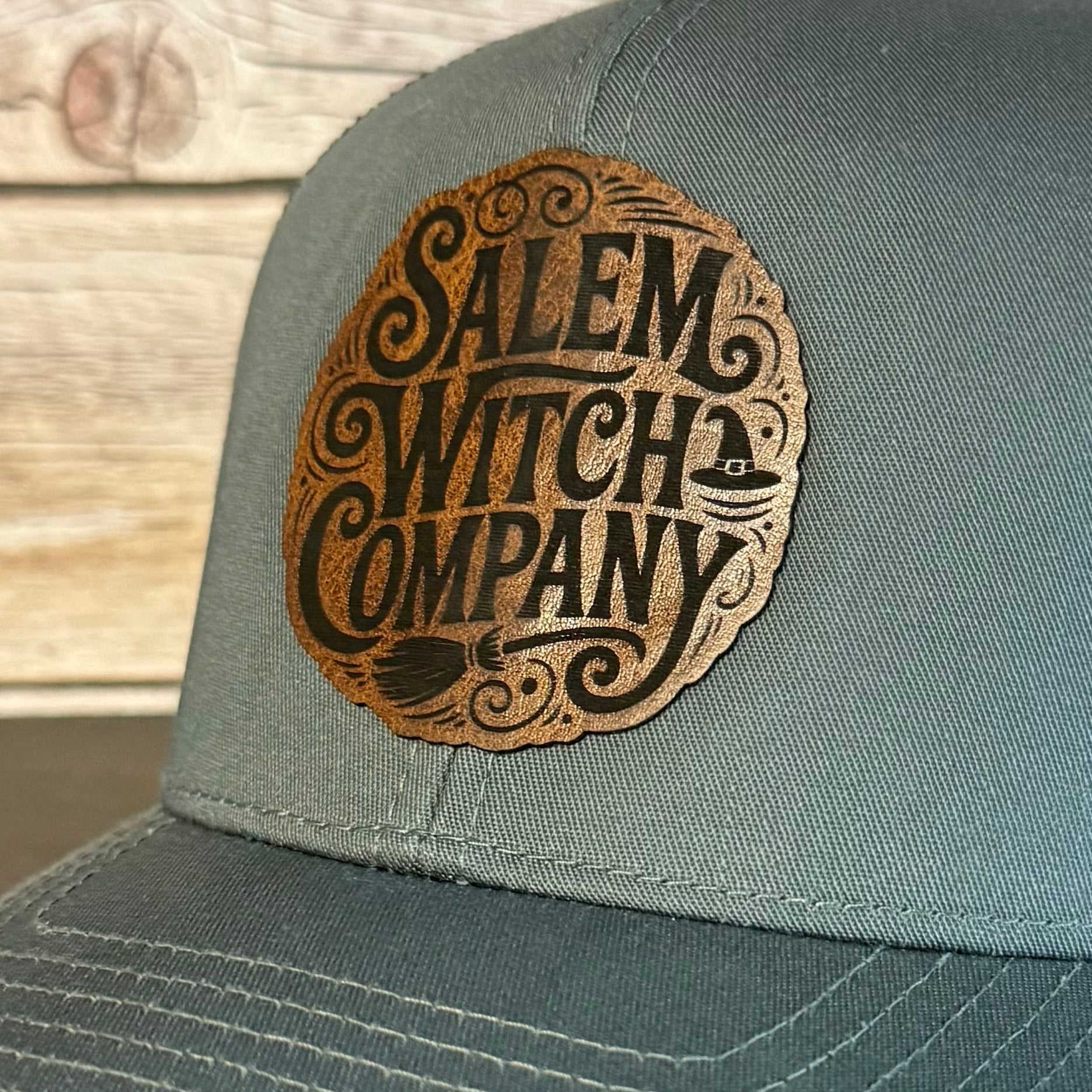 Gray cap with 'Salem Witch Company' logo on a wooden surface