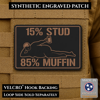 15% Stud 85% Muffin Funny Dad Bod laser-engraved synthetic morale patch: a rectangular black synthetic patch with tan engraved text and graphic, shown attached to tan tactical vest fabric. The patch reads “15% STUD 85% MUFFIN” with.
