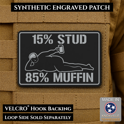 15% Stud 85% Muffin Funny Dad Bod laser-engraved synthetic morale patch: a rectangular black synthetic patch with white engraved text reading “15% STUD 85% MUFFIN” and a white reclining figure graphic, shown attached to tan.