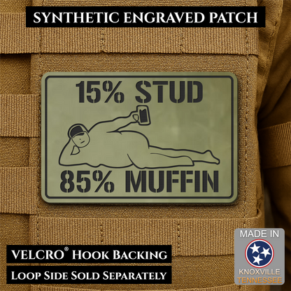 15% Stud 85% Muffin Funny Dad Bod laser-engraved synthetic morale patch: a rectangular synthetic engraved patch mounted on tan tactical vest loops. The patch is olive drab green with black text reading '15% STUD 85% MUFFIN' and a.