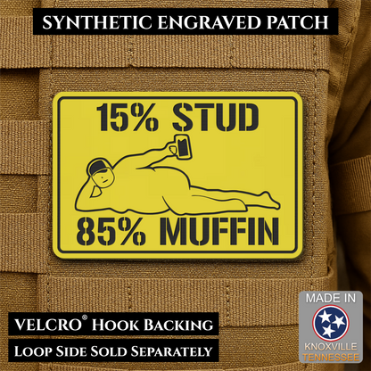 15% Stud 85% Muffin Funny Dad Bod laser-engraved synthetic morale patch: a yellow rectangular synthetic engraved patch with black text reading '15% STUD 85% MUFFIN' and a black line drawing, shown attached to tan tactical vest.