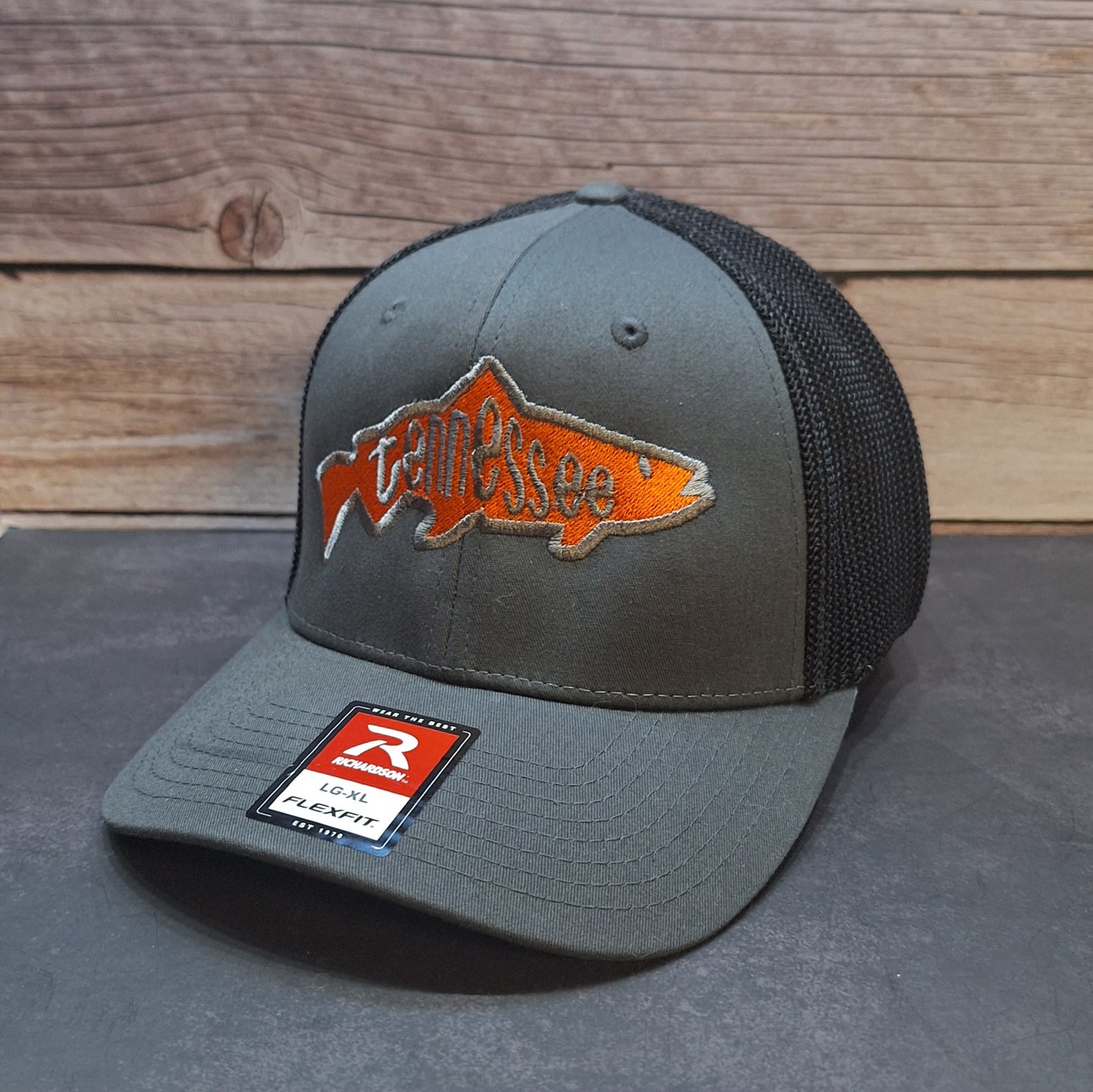 Gray cap with orange fish logo and brand label on a wooden background