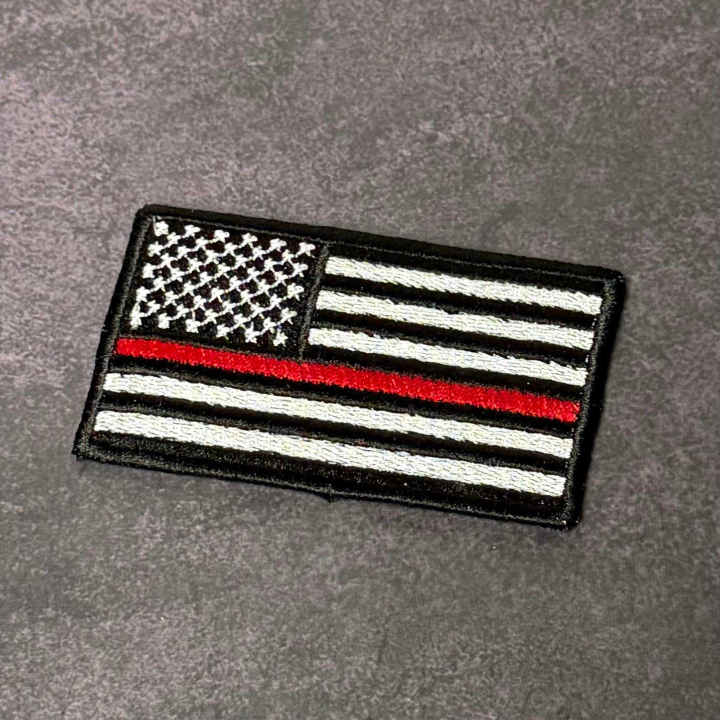 Thin Red Line American Flag embroidered firefighter morale patch with hook backing attached to tactical vest