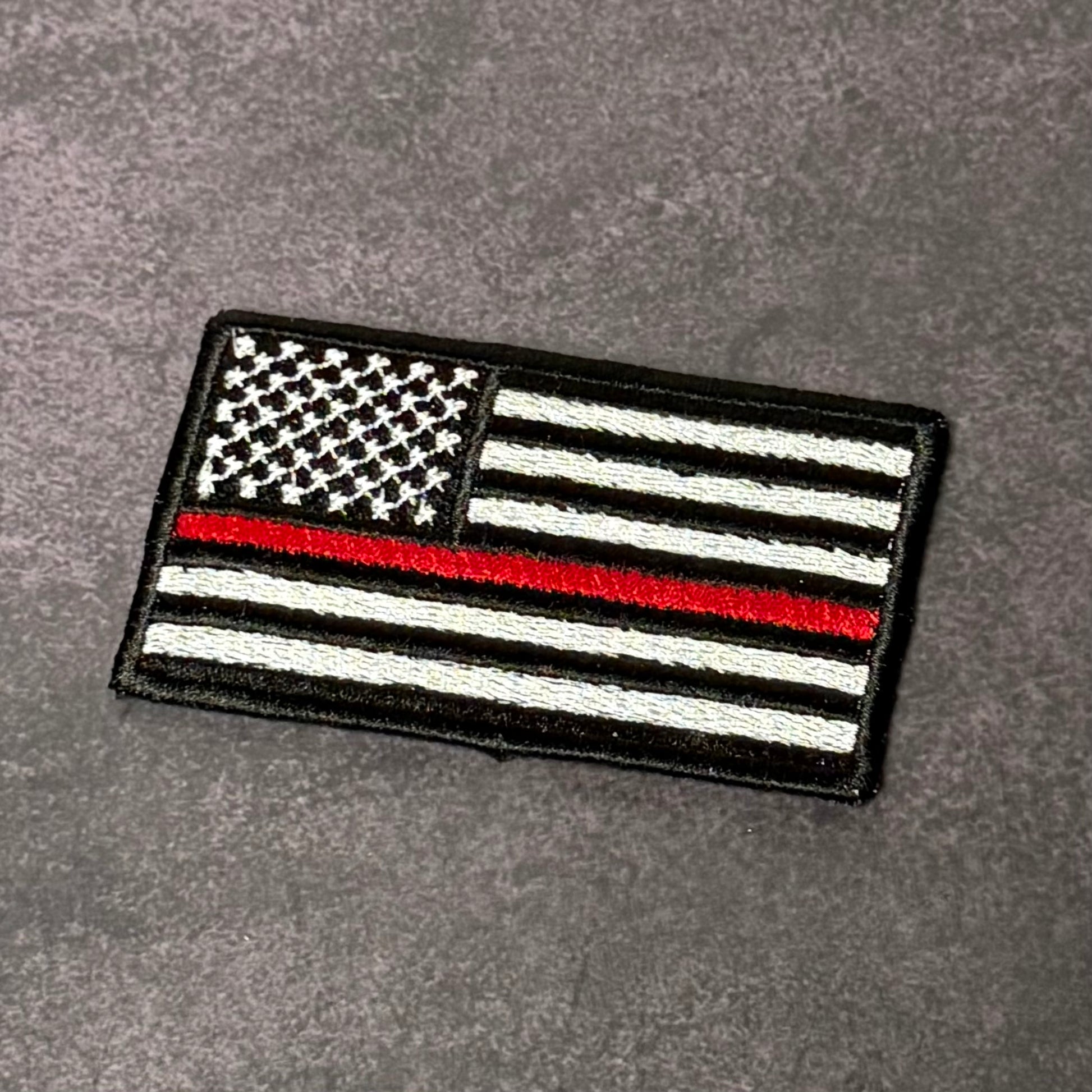 Thin Red Line American Flag embroidered firefighter morale patch with hook backing attached to tactical vest