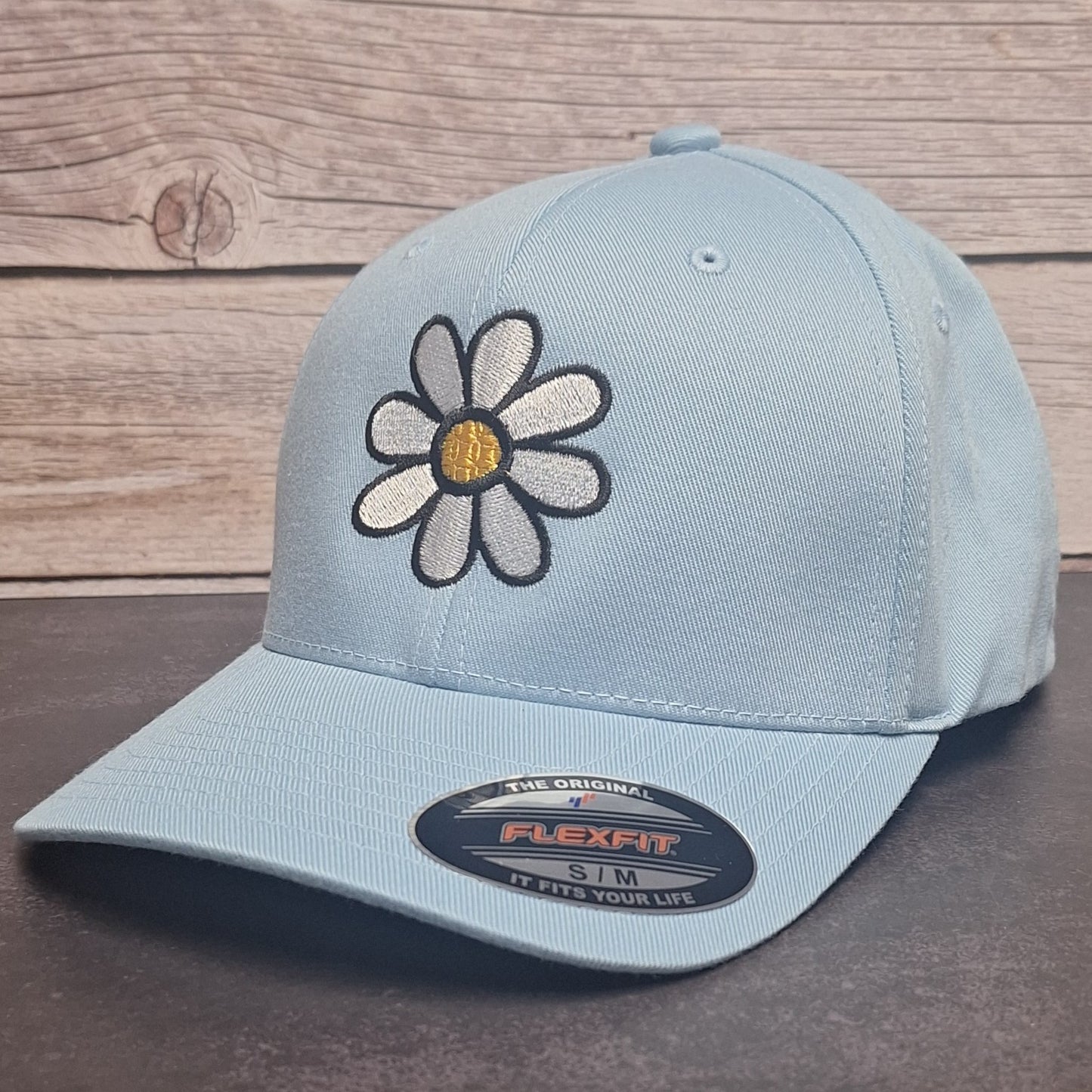 Light blue cap with a daisy flower design on a wooden surface