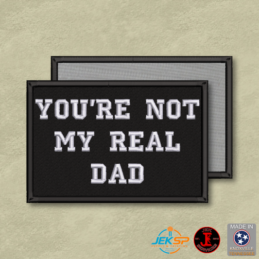 You're Not My Real Dad funny embroidered morale patch with white lettering on black background and Velcro® hook backing.